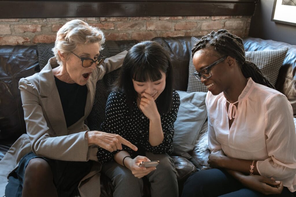 Three women of different ethnicities sharing a light-hearted moment indoors.